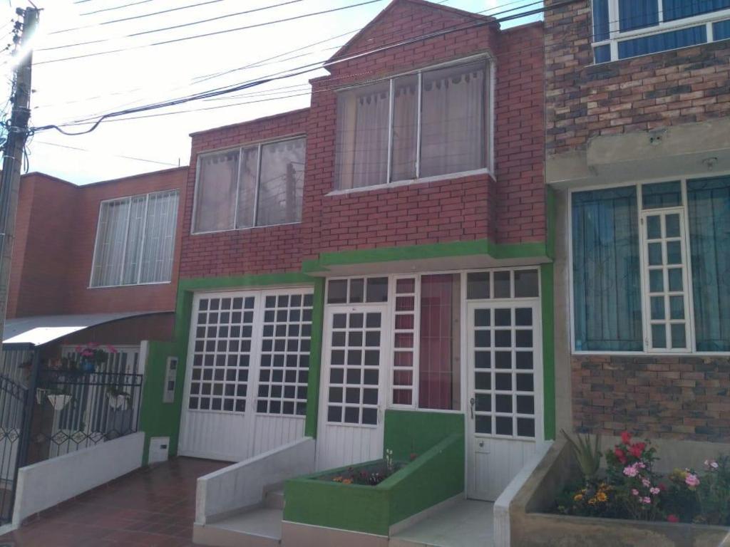 een stenen huis met witte en groene deuren bij Alojamiento en el centro de Paipa in Paipa