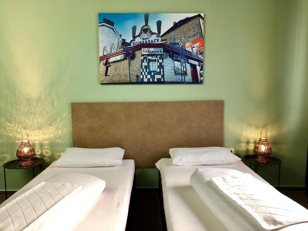 two beds in a room with a picture on the wall at Sandmann Boutique Hostel Hotel in Hamburg