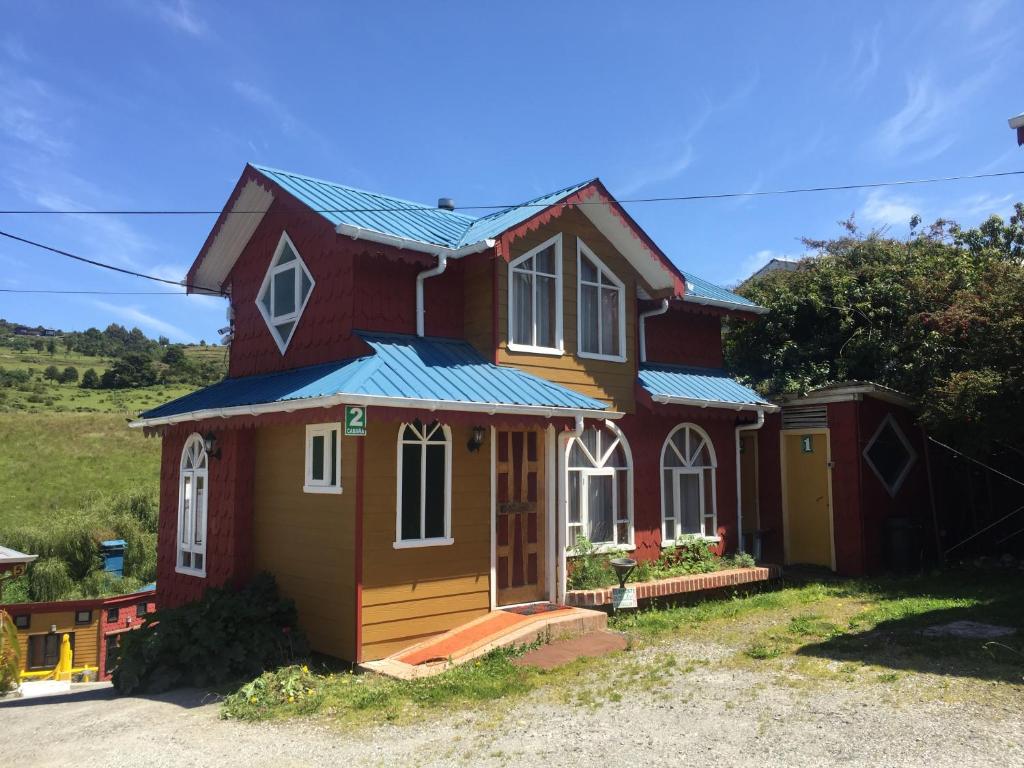 una pequeña casa roja con techo azul en Cabañas Encantos, en Castro