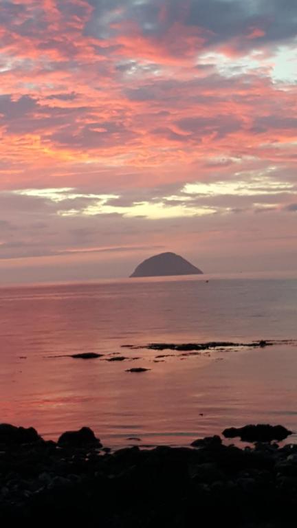 Wyspa w oceanie z zachodem słońca na niebie w obiekcie Clach Mhor w mieście Girvan