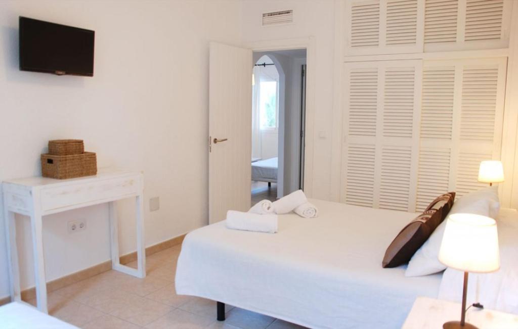 biała sypialnia z łóżkiem i telewizorem w obiekcie Apartamentos CostaMar 1; Apartamento nº11 w mieście Es Pujols