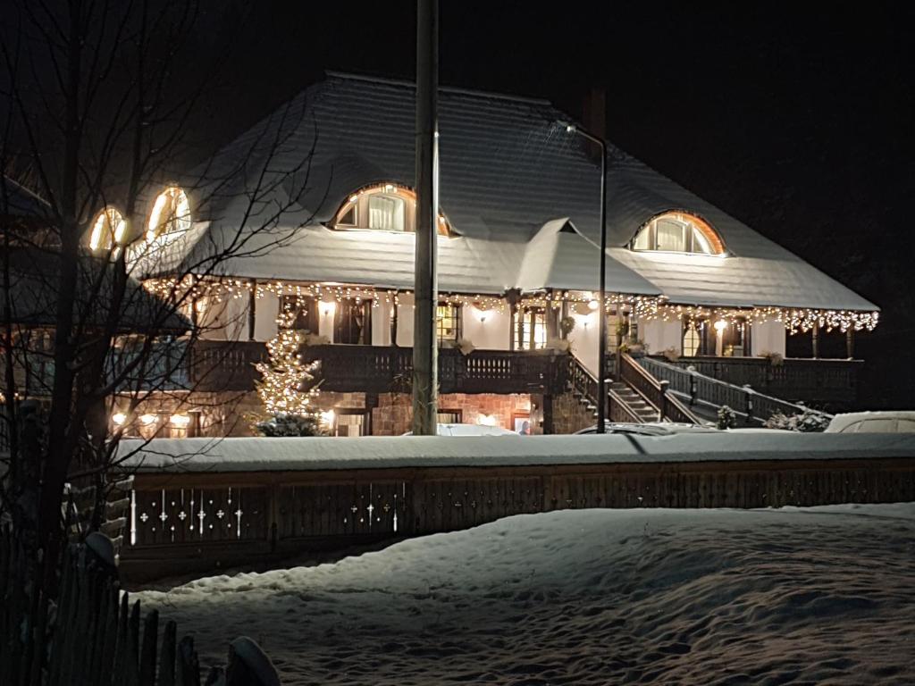 a building with christmas lights on it in the snow at Pensiunea La Moară in Fundu Moldovei