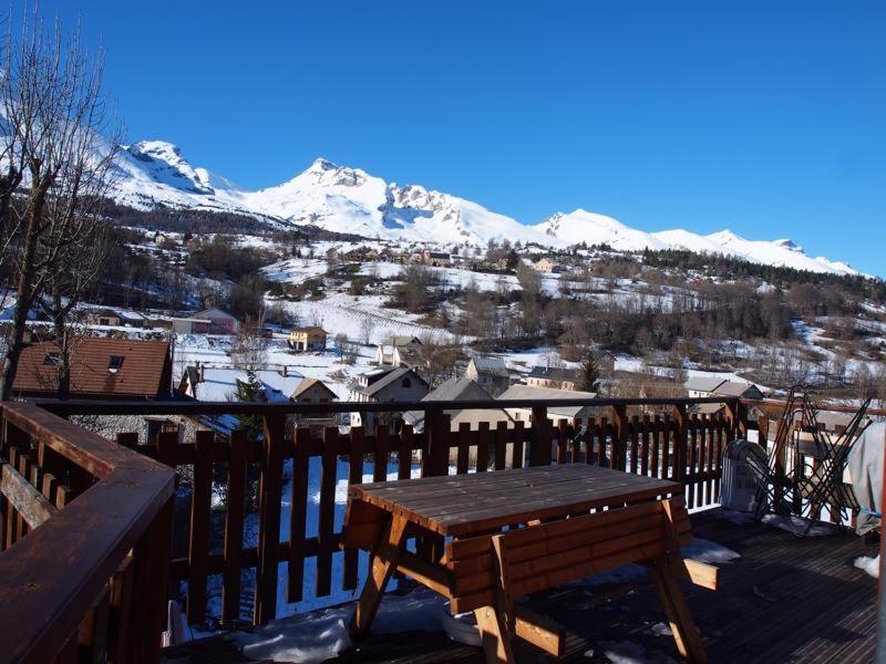 una mesa de madera en una terraza con una montaña cubierta de nieve en Chalet le 22 Agniéres, en Le Dévoluy