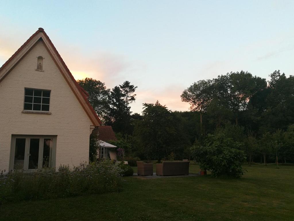 a white house in a yard with a sunset in the background at B&amp;B Asbeek in Asse