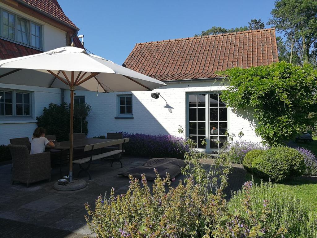 a woman sitting at a table under an umbrella at B&amp;B Asbeek in Asse