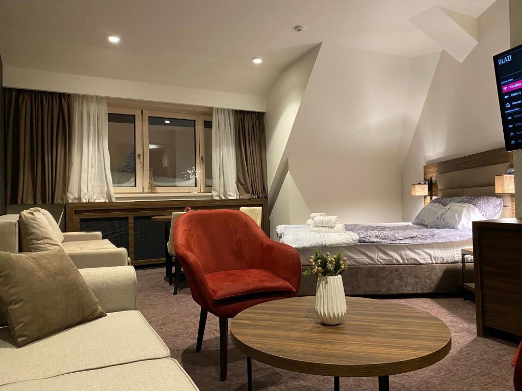 コパオニクにあるTeddy Apartman Kula Konaciのベッド、ソファ、テーブルが備わるホテルルームです。