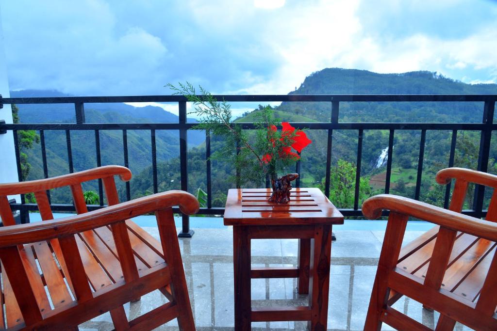 a balcony with two chairs and a table with flowers on it at La Montagna in Ella