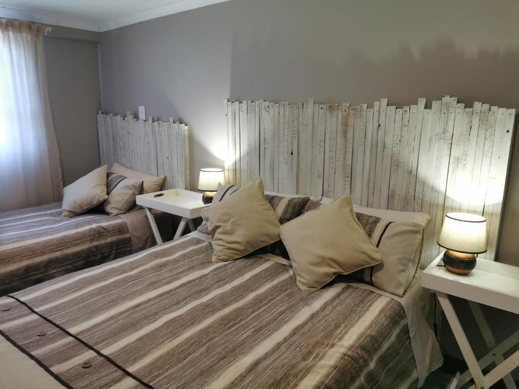 a bedroom with two beds and two tables with lamps at Kom Kuier Self-Cater in Vredenburg