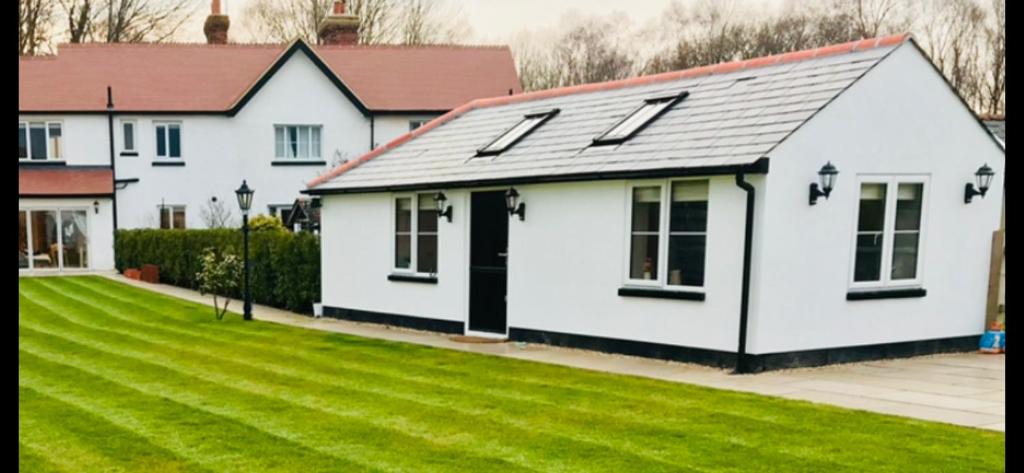 a white house with a black roof and a yard at The piggery in Pirbright