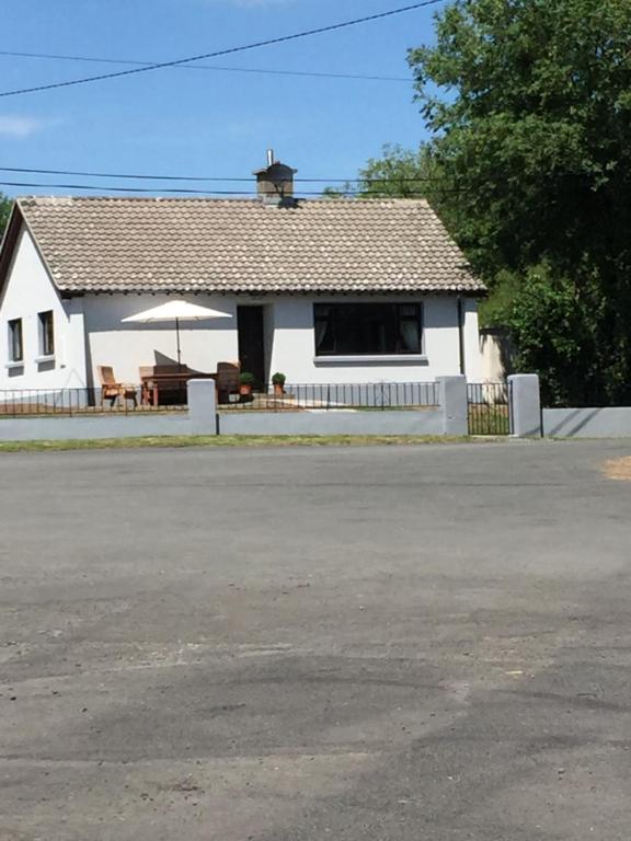 a white house with a porch and a table and umbrella at Kits Lodge Crover in Cavan