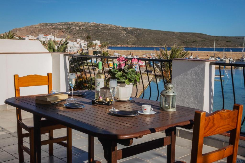 a wooden table on a balcony with a view of the ocean at Apartamentos Gabriel Sans in Fornells