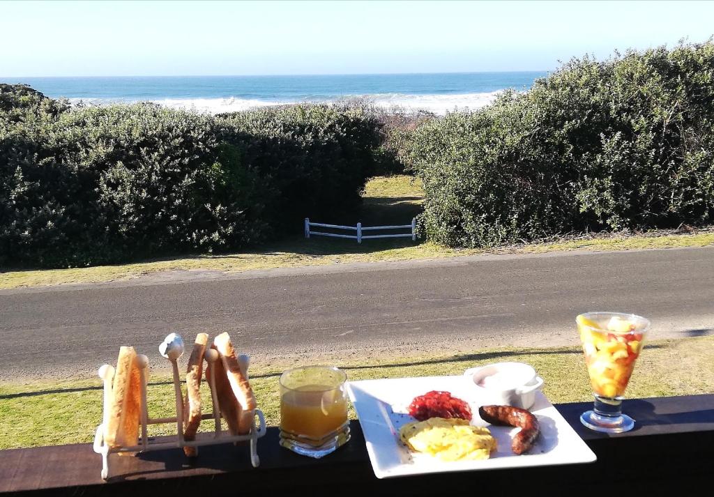 um prato de comida de pequeno-almoço numa mesa com vista para o oceano em Versailles B and B em Gonubie