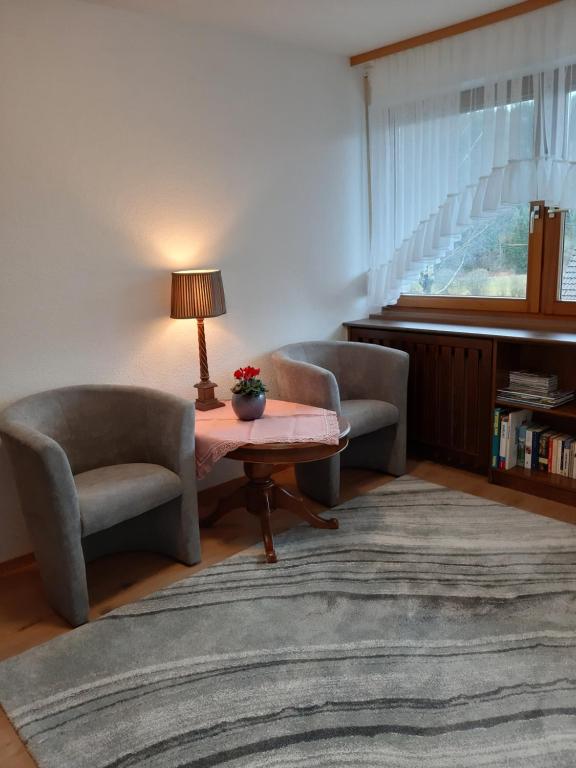 ein Wohnzimmer mit 2 Stühlen und einem Tisch mit einer Lampe in der Unterkunft Ferienwohnung Viktoria in Lenzkirch