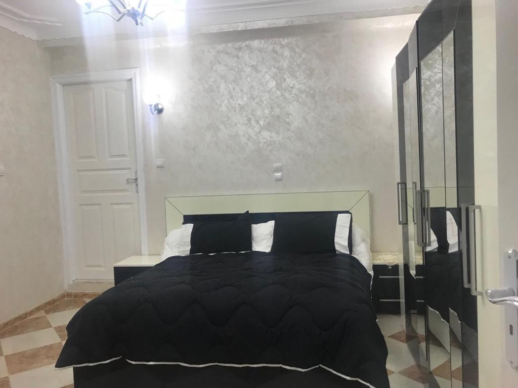 1 dormitorio con 1 cama con edredón negro en Super appartement de luxe T4 a la ville de Bejaia en Bugía