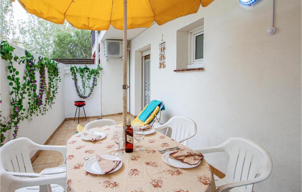 einen Tisch mit weißen Stühlen und einem Sonnenschirm in der Unterkunft 1 Bedroom Cozy Apartment In Sant Antoni De Calo,,, in Sant Antoni de Calonge