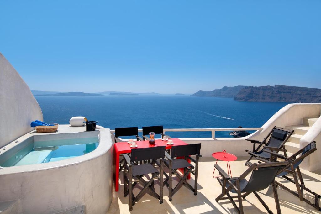 eine Terrasse mit Tisch und Stühlen neben einem Swimmingpool in der Unterkunft Satori Caves by Thireon in Oia
