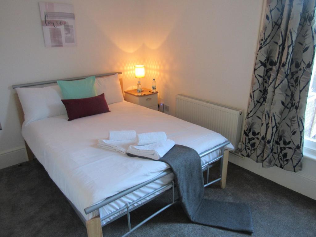 Un pequeño dormitorio con una cama blanca y una ventana en The Tas Suites - Tas Accommodations en Cambridge