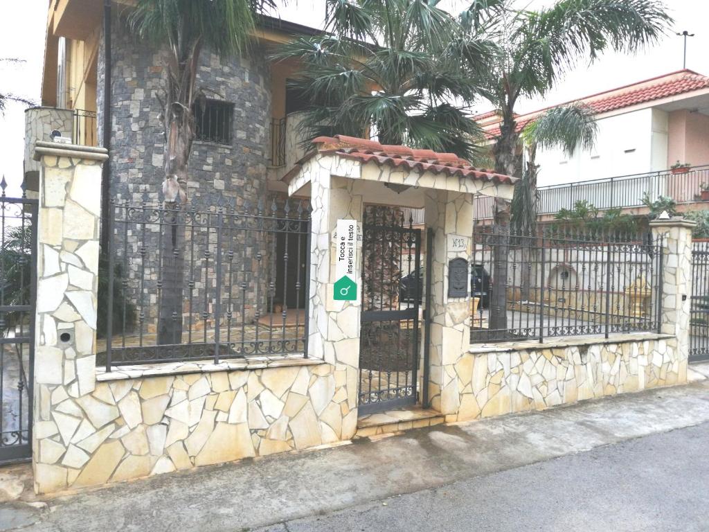 a stone building with a gate and a fence at Villa Aurora Per Vacanze in Palermo