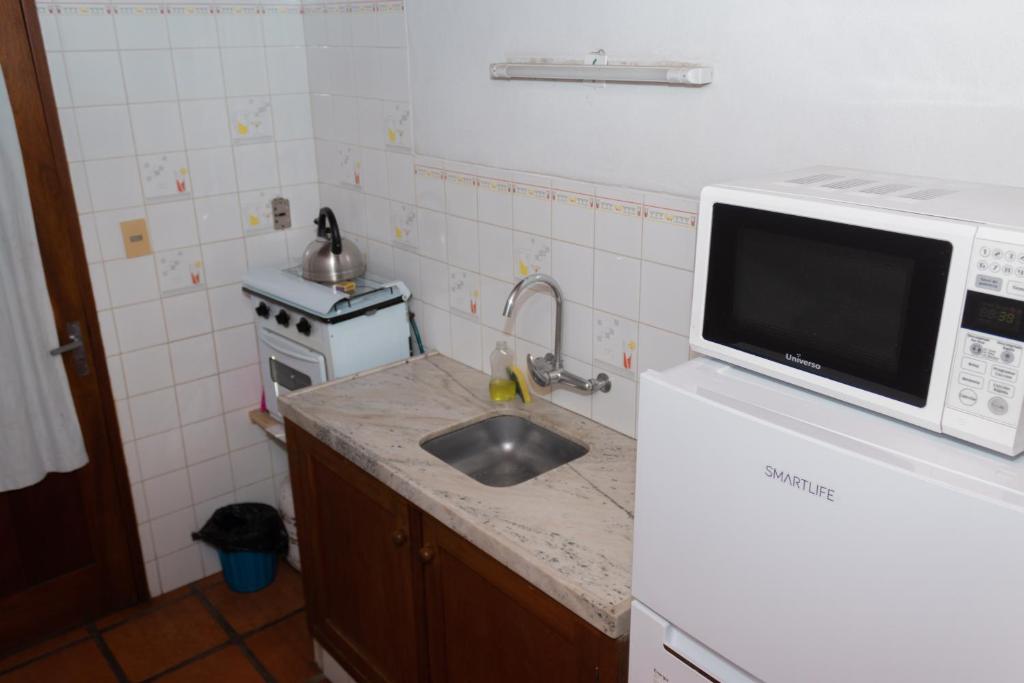 a kitchen with a sink and a microwave at Hostal Canela in Termas del Daymán