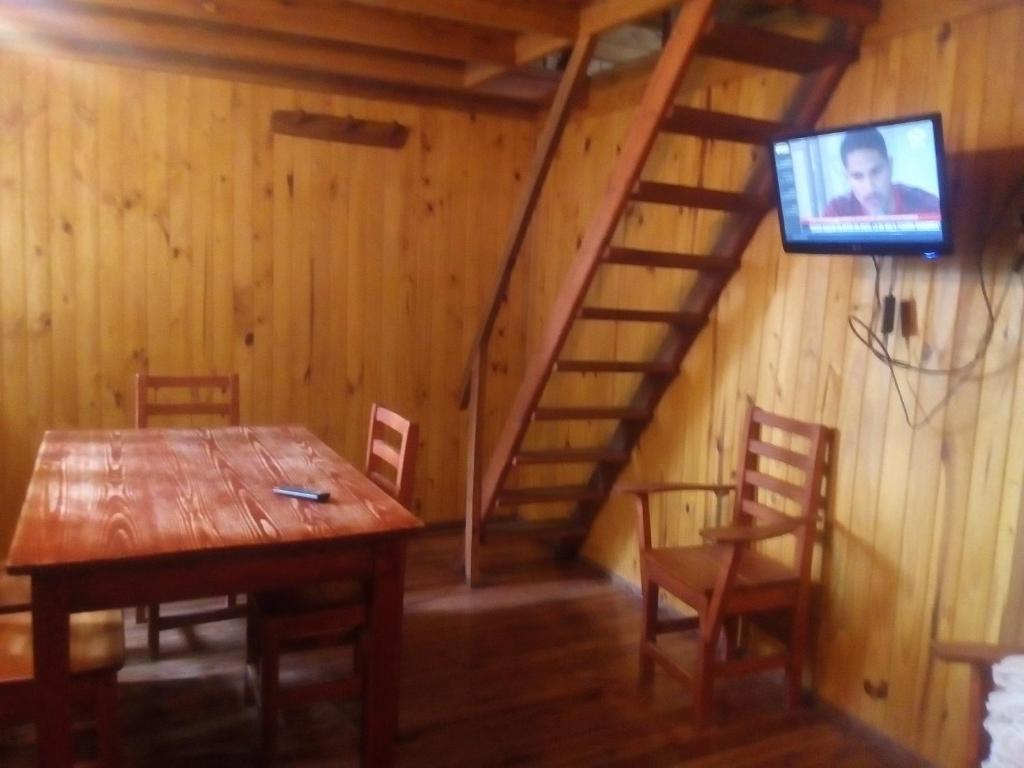 a dining room with a table and a tv on a wall at Cabañas Teushen in Perito Moreno