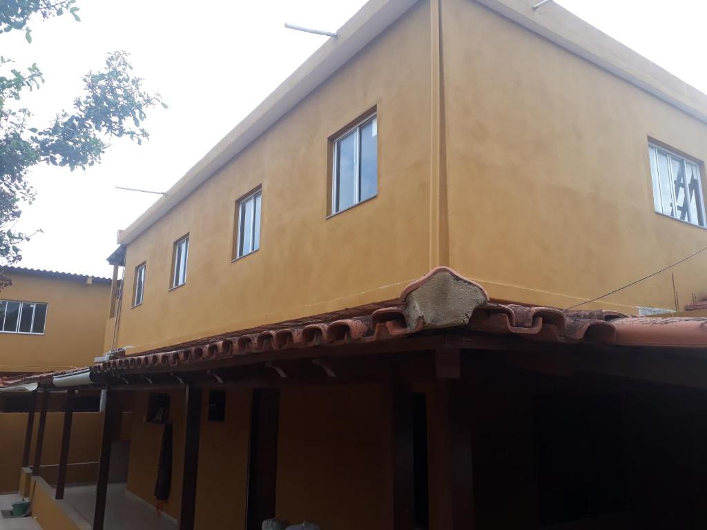 un bâtiment jaune avec des fenêtres au-dessus dans l'établissement Hospedagem da Rose, à Marataizes