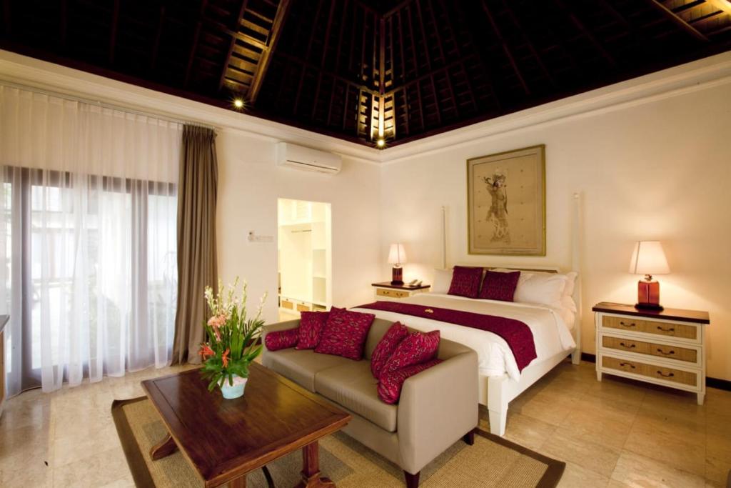 a bedroom with a bed and a couch and a table at Avillion Villa Cinta @Sanur, Bali in Sanur