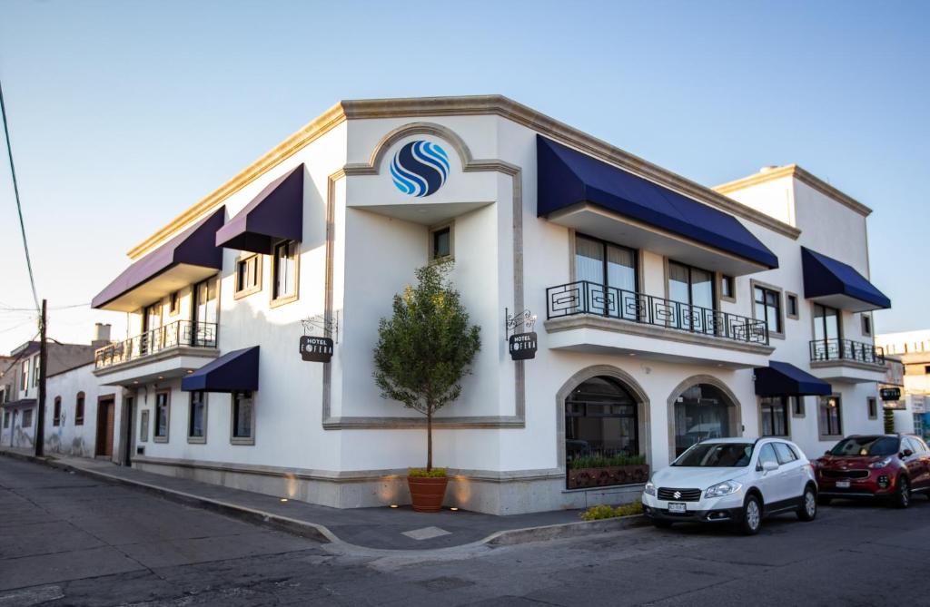 duży biały budynek z niebieskimi markizami w obiekcie Hotel Esfera Tulancingo w mieście Tulancingo