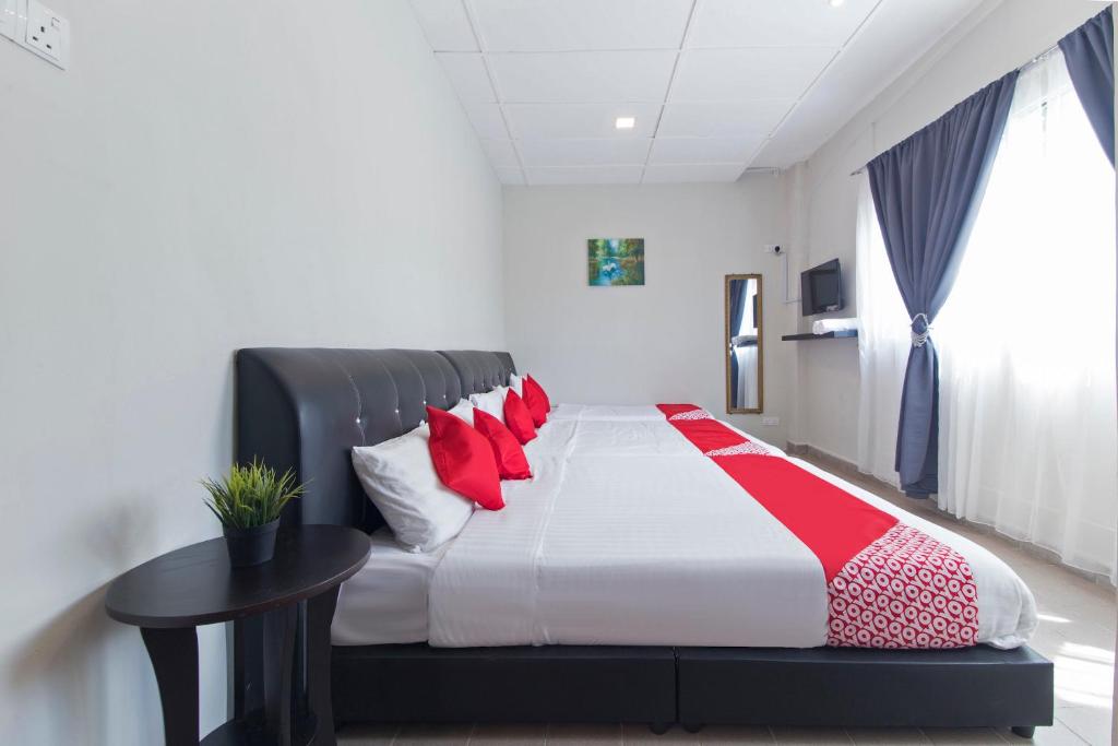 - une chambre avec un lit doté d'oreillers rouges et d'une table dans l'établissement OYO 1189 Big C Motel, à Kuah