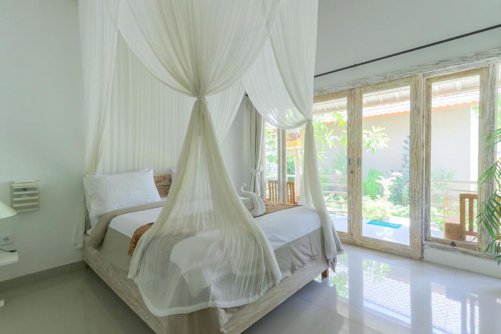 a bedroom with a bed with a mosquito net at Angels Bungalow Nusa Penida in Nusa Penida