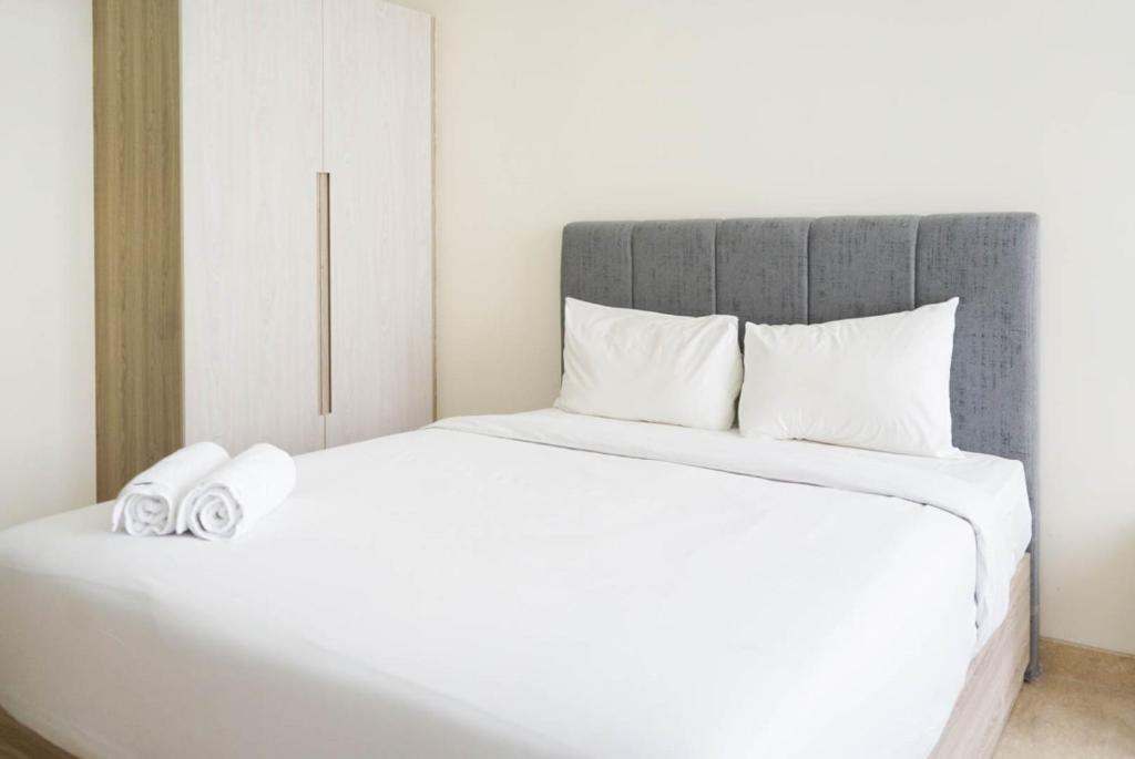 a bedroom with a white bed with towels on it at Minimalist and Homey Studio Menteng Park Apartment By Travelio in Jakarta