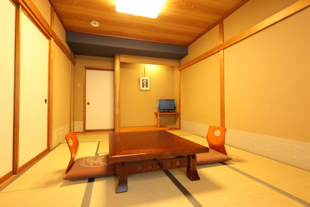 a room with a wooden table and a television at Hotel Taigakukan in Hakuba