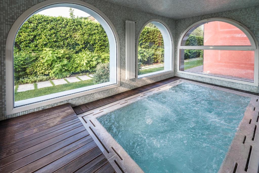 una piscina coperta con tre finestre in una casa di Acqua Resorts a Sirmione