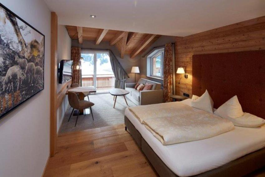 a bedroom with a bed and a living room at Alpenjuwel Rohnenspitze in Zöblen