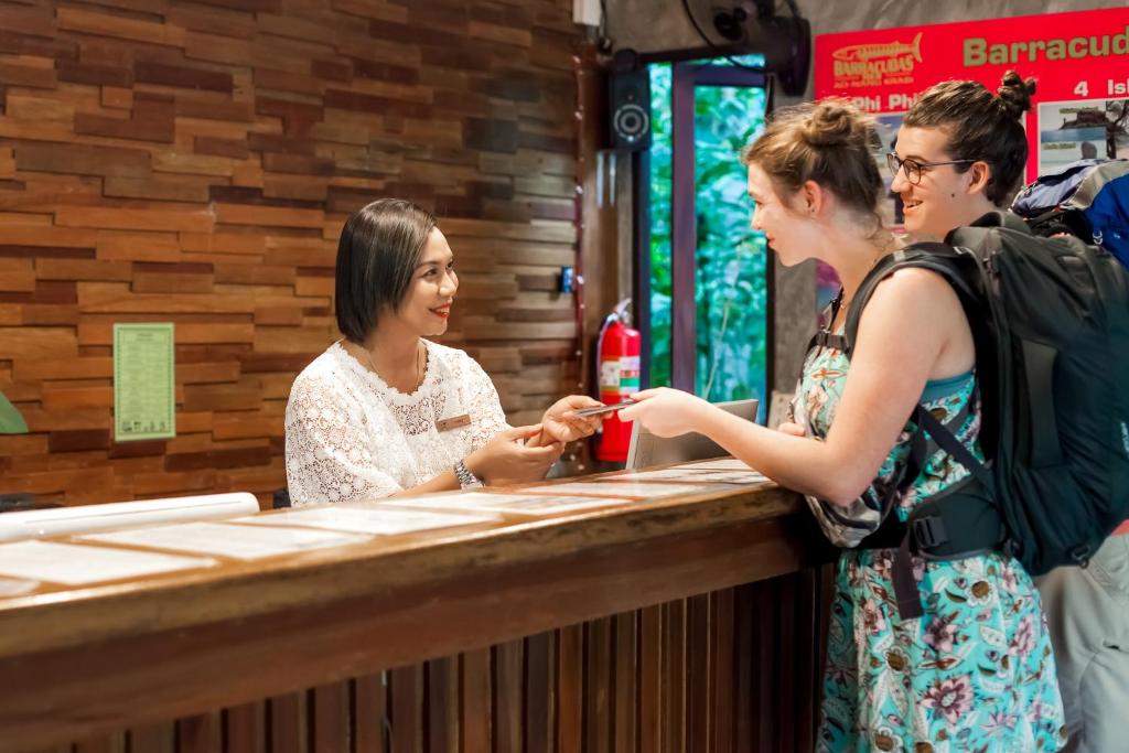 奥南海滩The Vatika Resort and Spa的两个女人站在酒吧里跟一个男人说话