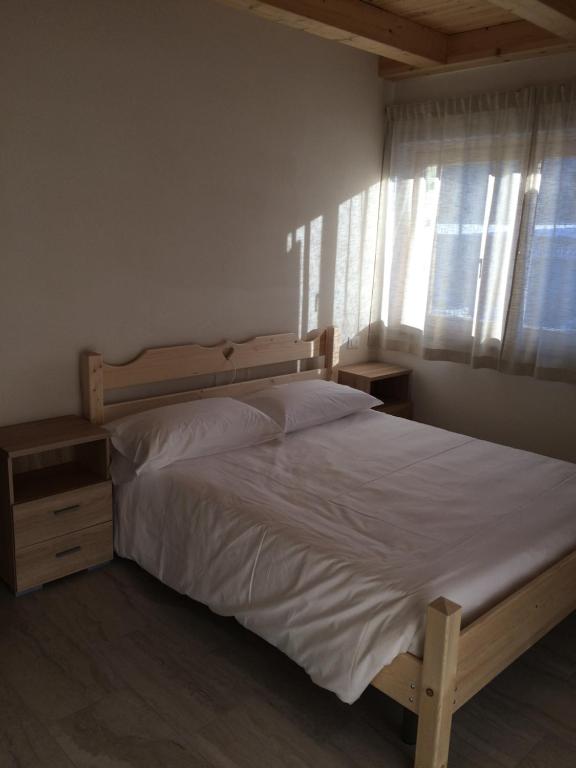 a bedroom with a bed with white sheets and a window at Da Alsido in Camporosso in Valcanale