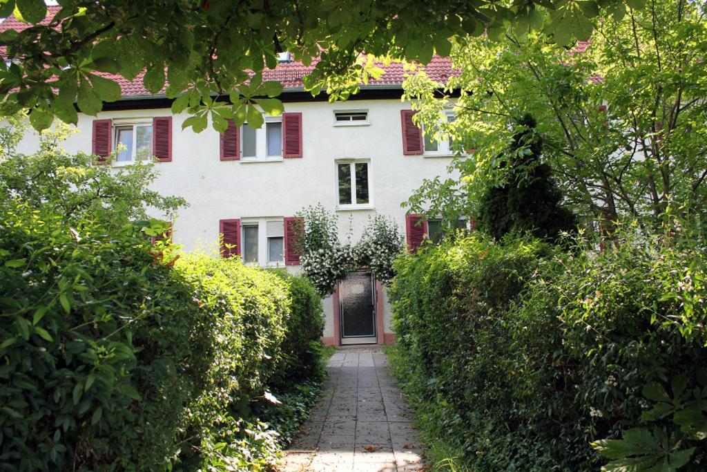 ein weißes Haus mit roten Rollläden und einem Gehweg in der Unterkunft Ferienwohnung am Salzsee in Bad Windsheim
