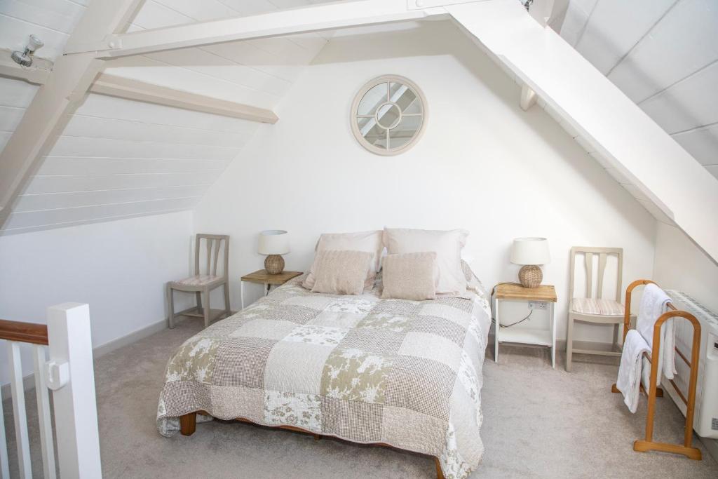 a white bedroom with a bed and two tables at The Old Chapel in Marlborough