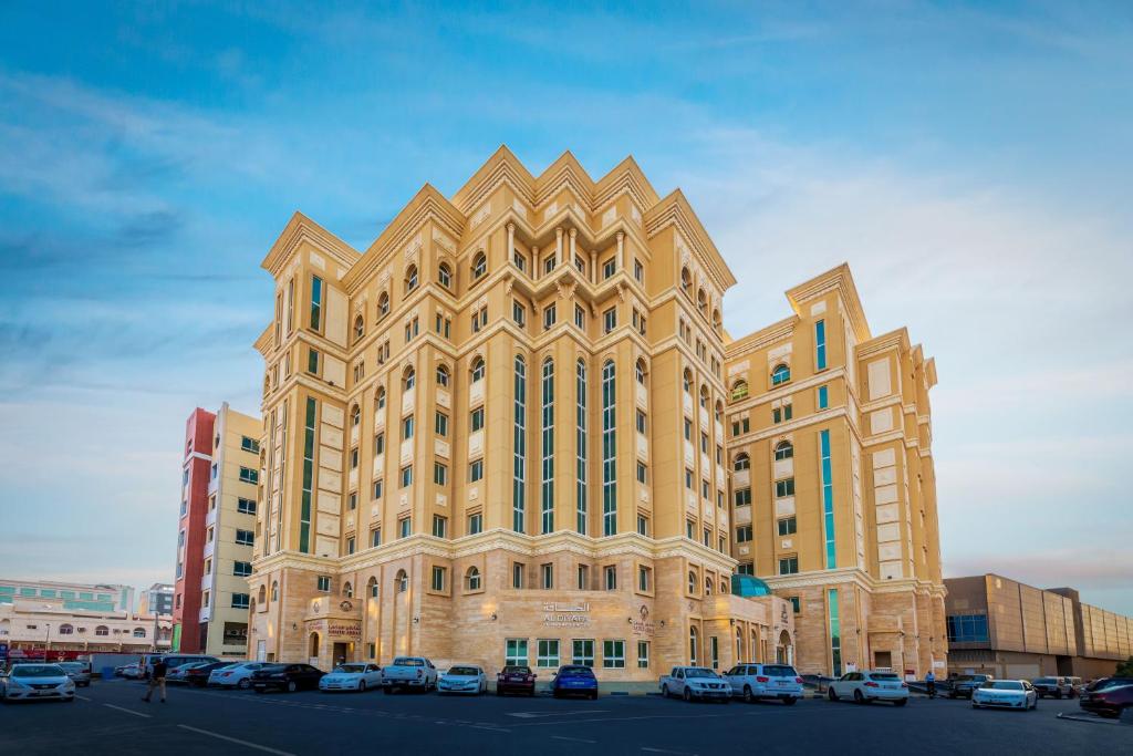 杜哈的住宿－Al Diyafa Furnished Suites，停车场内停放汽车的大型建筑
