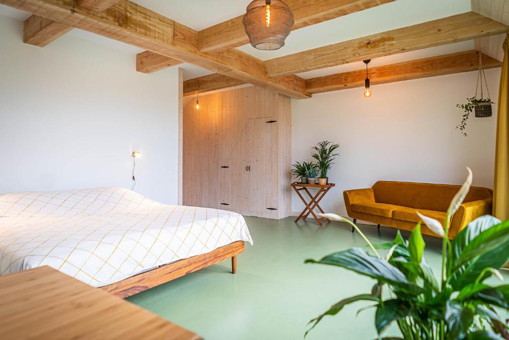 ein Schlafzimmer mit einem Bett, einem Stuhl und einem Tisch in der Unterkunft Wijngaard de Kroon van Texel in Den Burg
