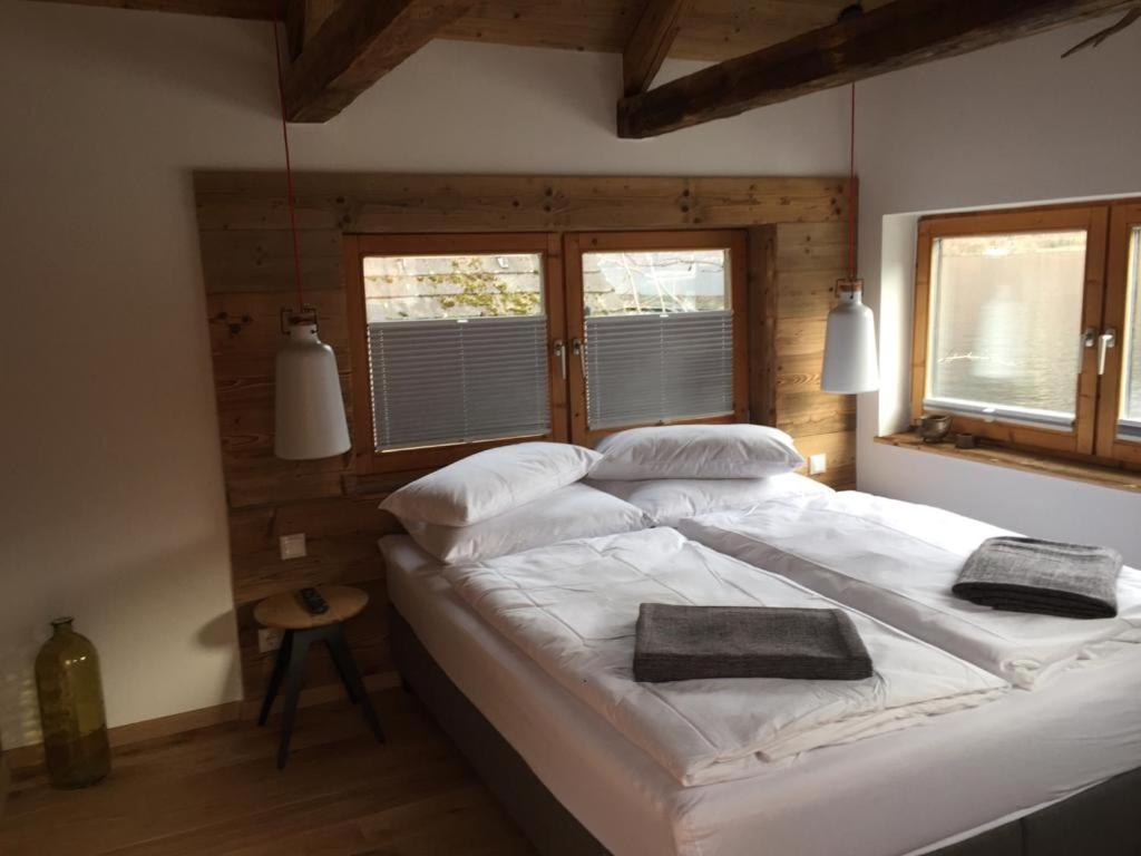 een groot wit bed in een kamer met 2 ramen bij Bootshaus am Hallstätter See in Hallstatt