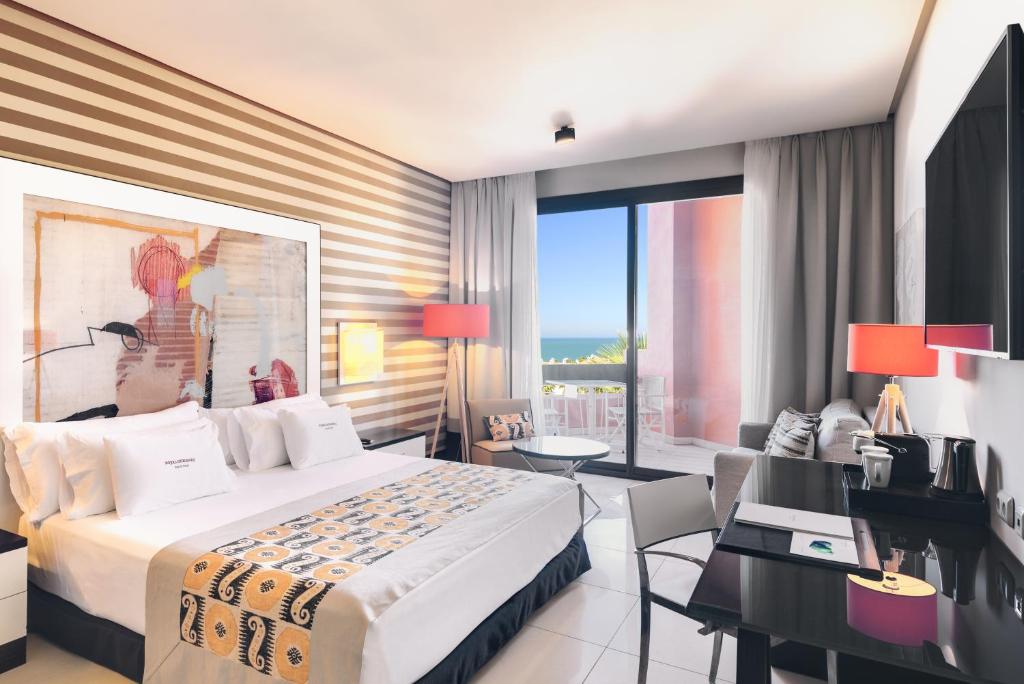 a hotel room with a bed and a desk and a room at Royal Hideaway Sancti Petri in Chiclana de la Frontera