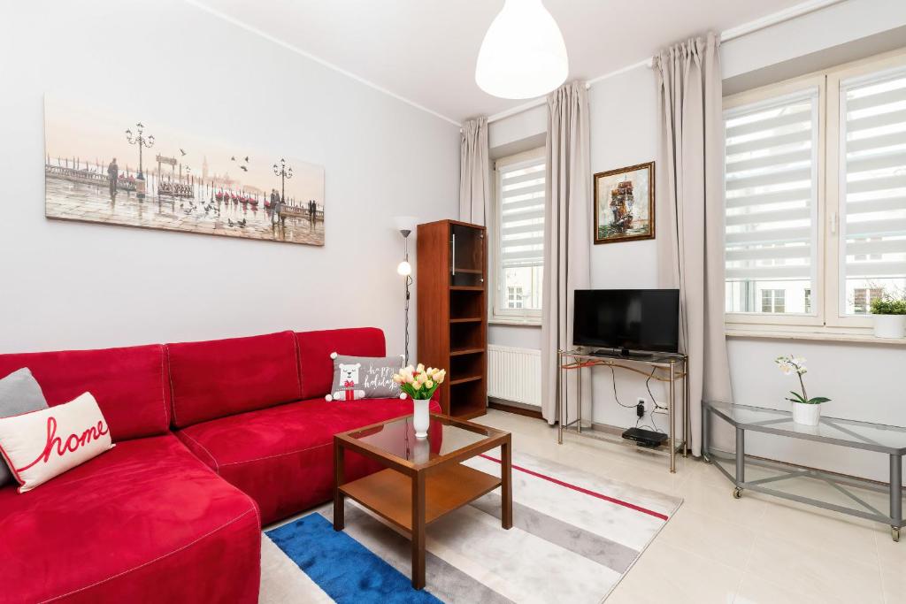 a living room with a red couch and a tv at Apartments Old Town Ogarna 107 by Renters in Gdańsk