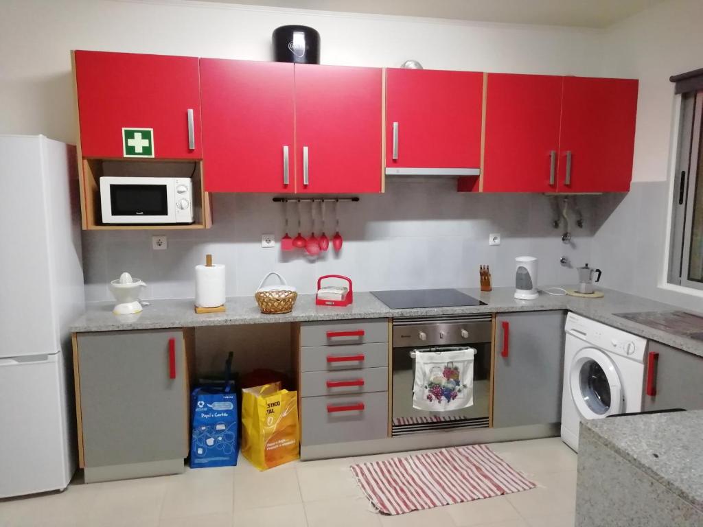 kuchnia z czerwonymi szafkami i pralką w obiekcie Cantinho do Diogo w mieście Calhetas
