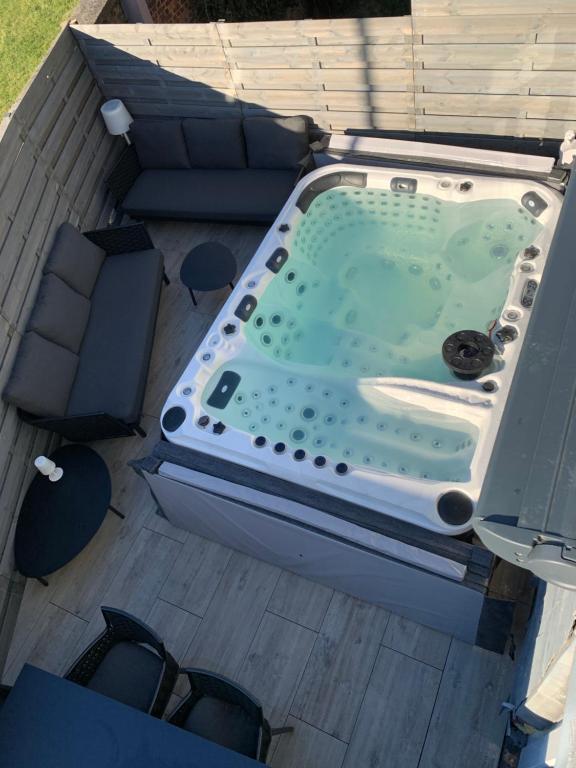 a hot tub on top of a deck with chairs at Maison avec Jacuzzi 5ch in Verviers