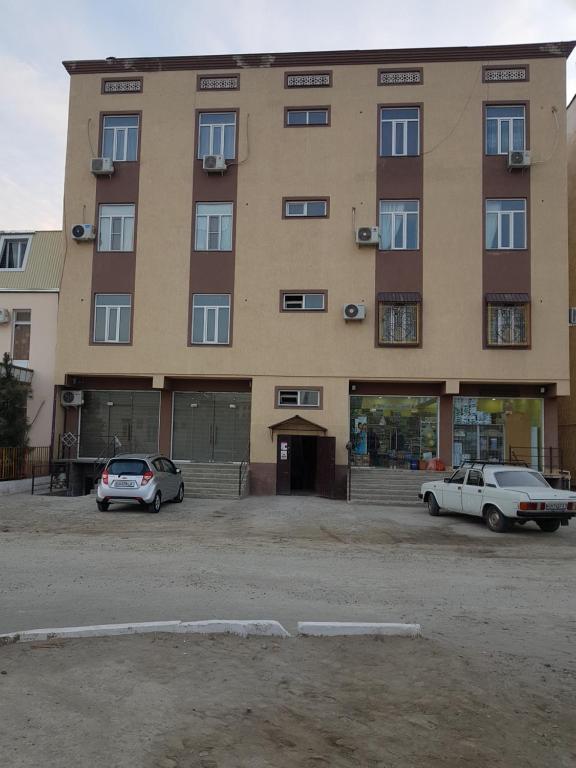 un gran edificio con dos coches estacionados frente a él en Элитная Квартира, en Bukhara
