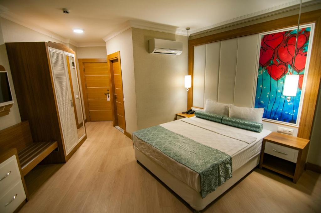 ein Schlafzimmer mit einem Bett und einem Wandgemälde in der Unterkunft Exelans Hotel in Fethiye