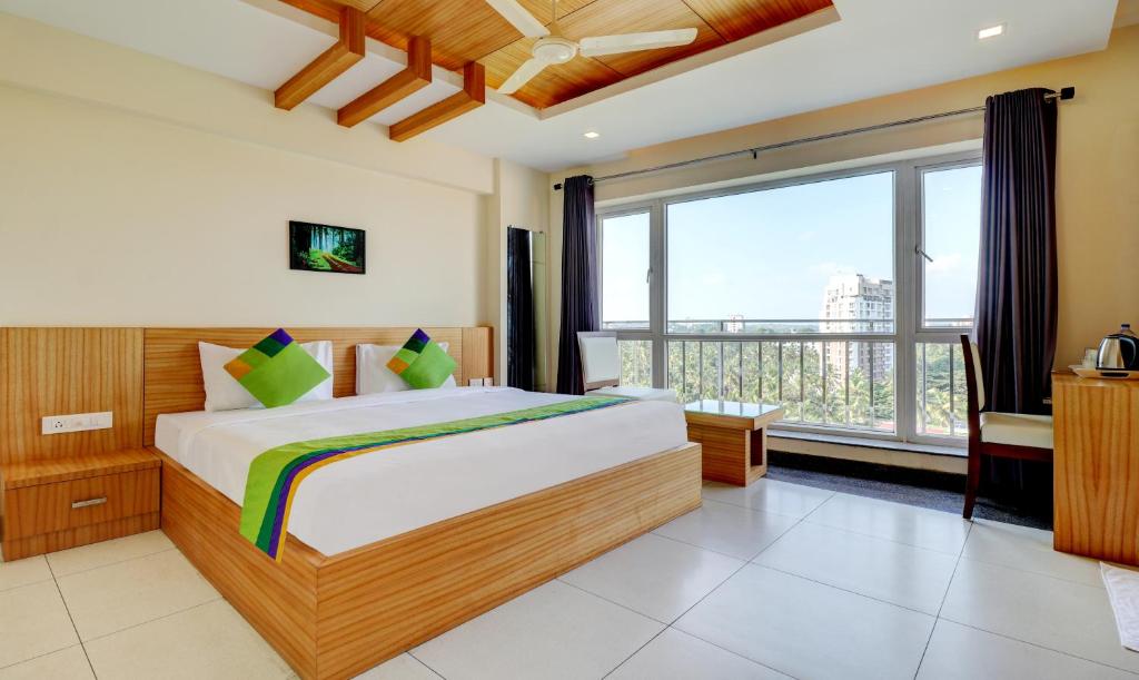 a bedroom with a large bed and a large window at Treebo Trend Park in Trivandrum