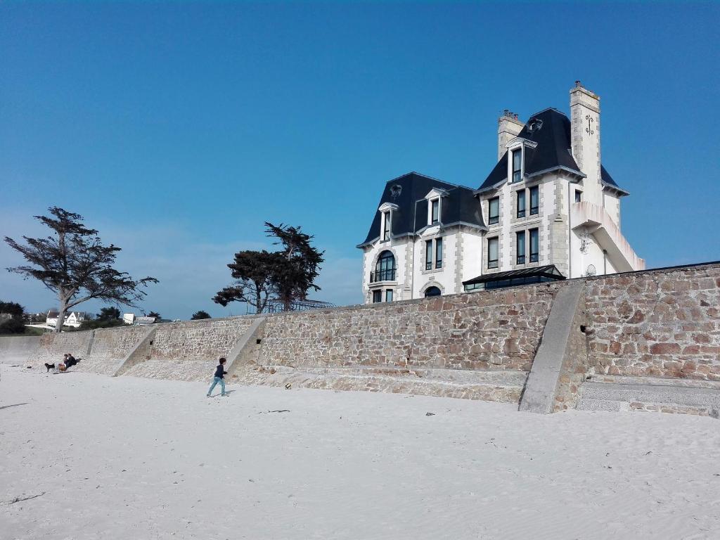 a person walking on the beach in front of a house at Château de Saint-Samson in Plougasnou