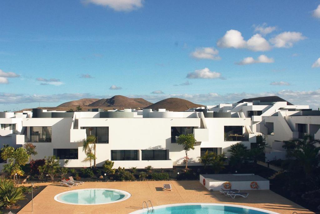 VillaverdeにあるSunset Apartment at Casilla de Costaの白い建物の景色を望む2つのプールが備わります。
