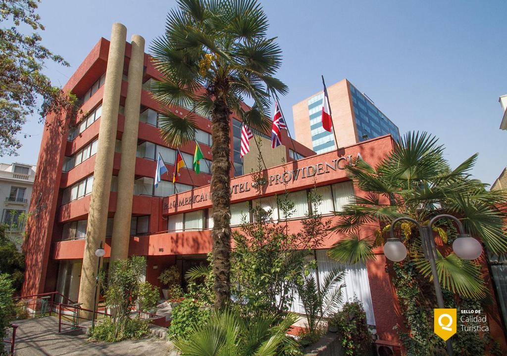 a building with a palm tree in front of it at Panamericana Hotel Providencia in Santiago